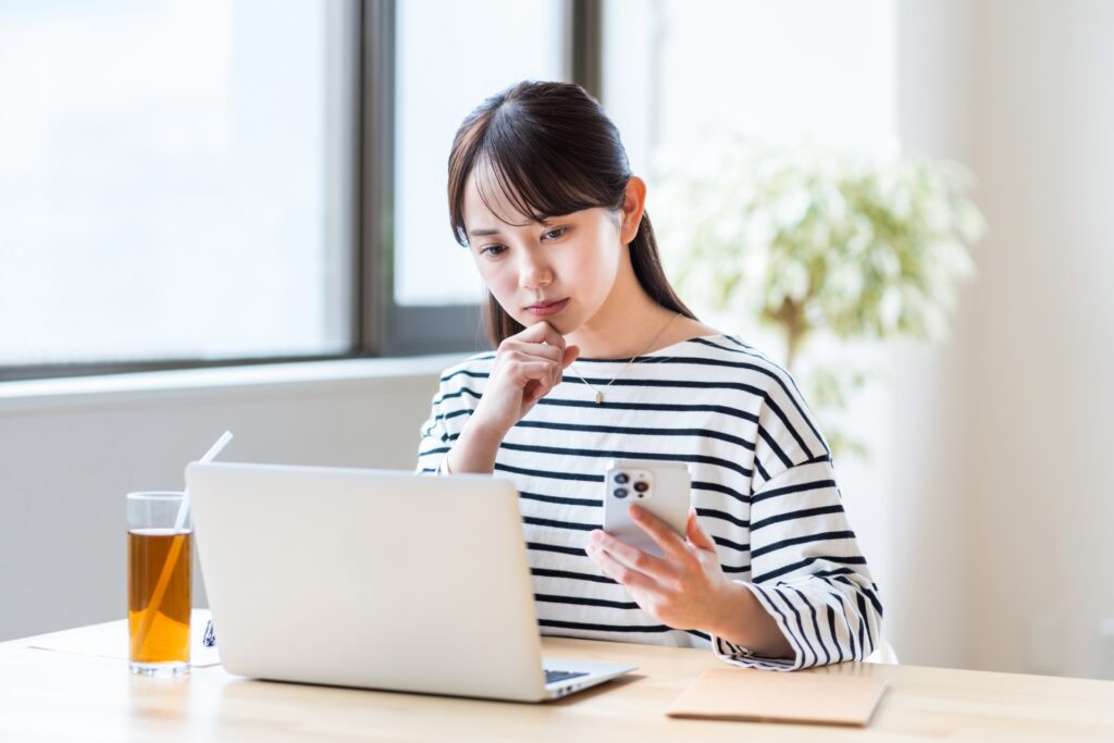 スマホとパソコンで視聴方法を調査している女性